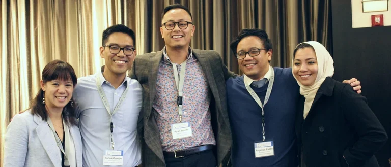 Group of scholars with lanyards smiling together at conference.