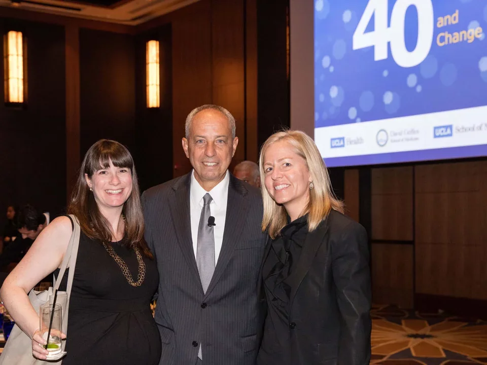 One man and two women clinician scholars standing in front of 40th celebration. 