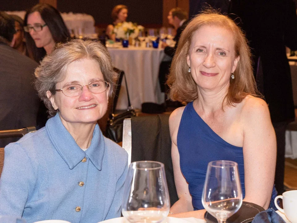 Carol Mangione and female colleague sitting at a celebration dinner.