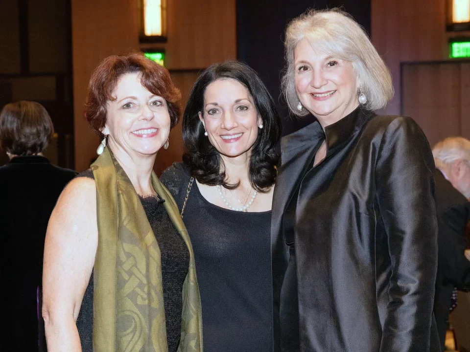 Three women smiling and dressed up for an awards celebration.