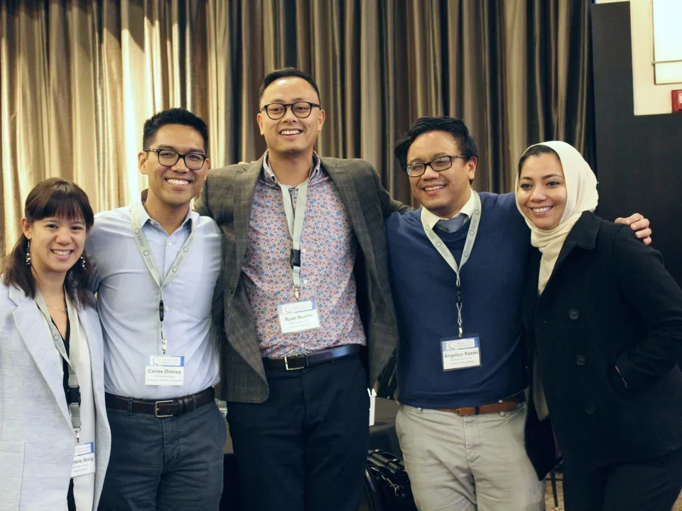 Group of scholars with lanyards smiling together at conference.