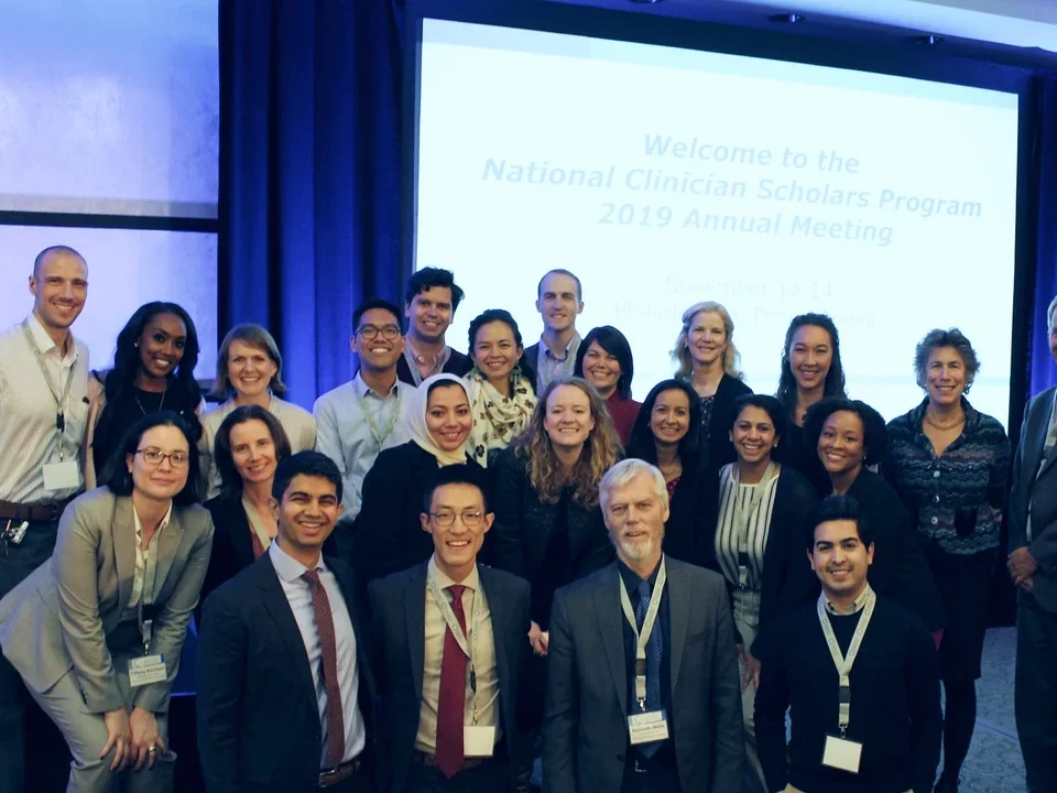 Group of male and female scholars in suits at annual meeting.