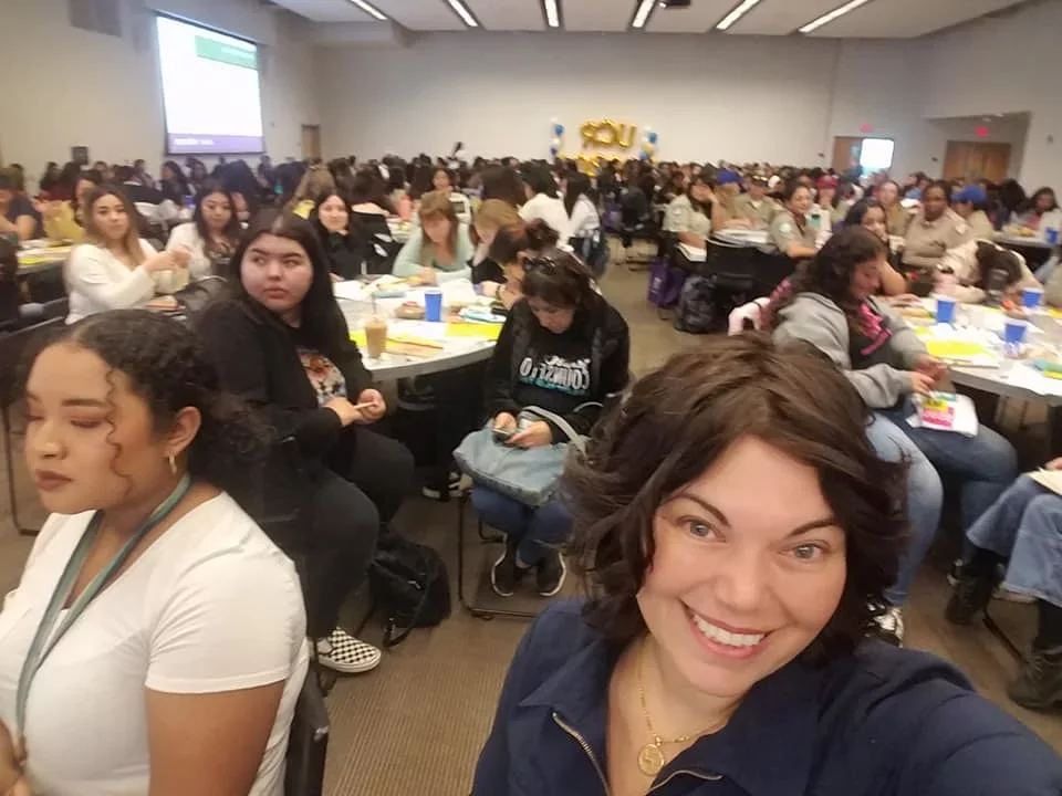 Two women at front of group sitting during work conference.